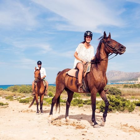 Young tourist couple horseback riding in Mallorca, Spain.
